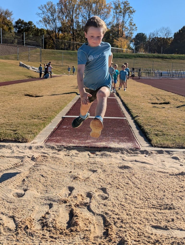 Flow Mo athlete jumping into sand pit.